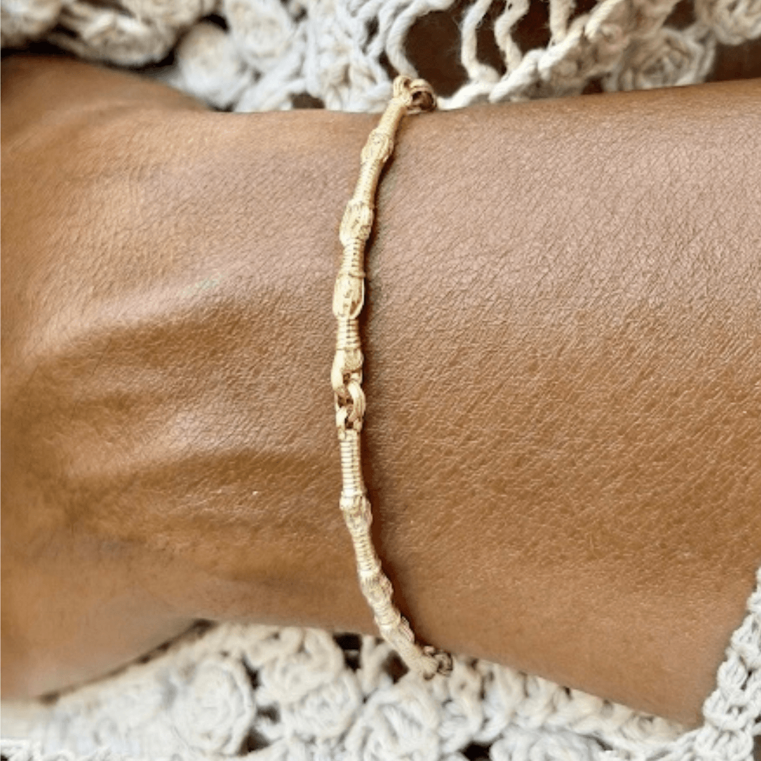 14K gold Tzitzit bracelet №1 worn by a female model in a cream crochet outfit.