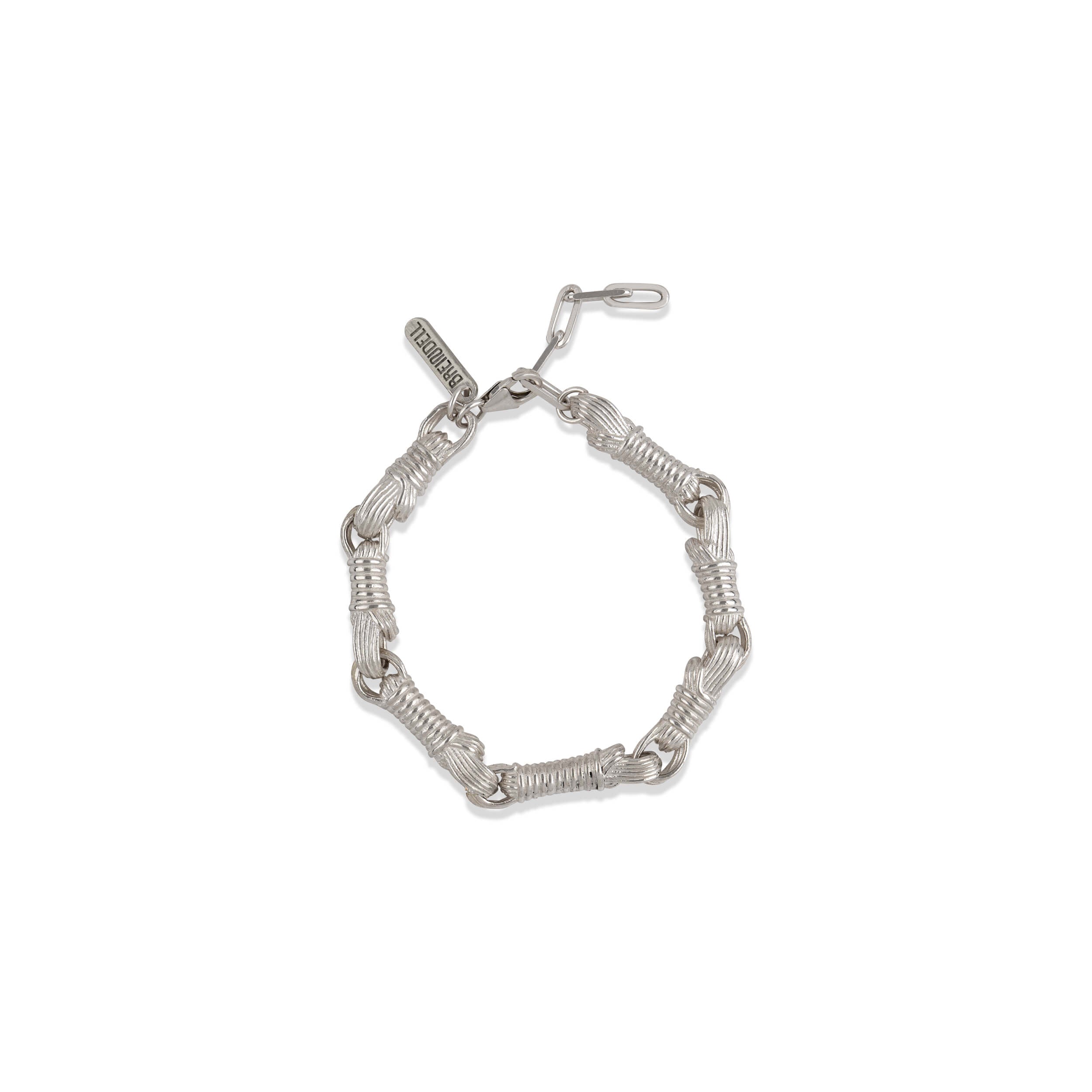 A minimalist flat lay of the Breindell Tzitzit I Bracelet №3 in 925 sterling silver. The composition highlights the balanced structural symmetry and architectural form of the integrated knot, presented with a clean, soft shadow on a stark white background.