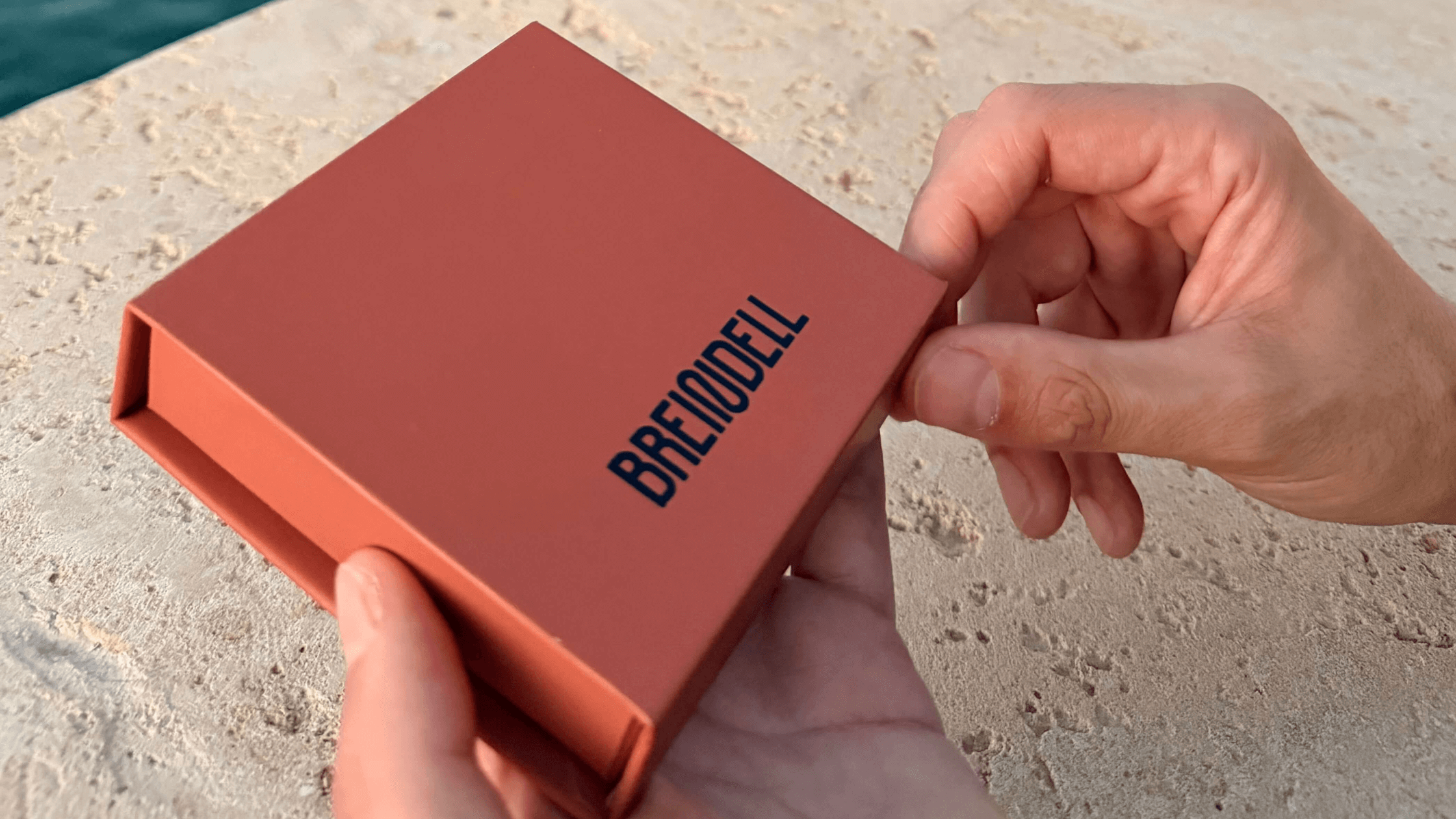 Man holding Breindell Jewish jewelry box on stone wall. 
